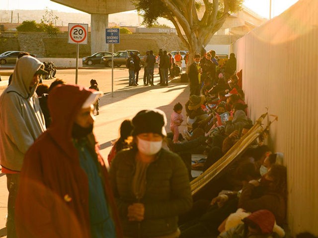 TOPSHOT - Asylum seekers wait outside the El Chaparral border crossing port as they wait to cross into the United States in Tijuana, Baja California state, Mexico on February 19, 2021. - The Biden administration plans to slowly allow 25,000 people with active cases seeking asylum into the US previously …