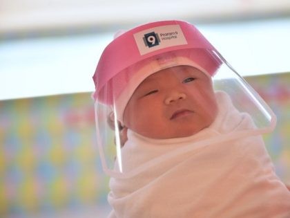 This photo taken through a glass window at a maternity ward shows a newborn baby wearing a face shield, in an effort to halt the spread of the COVID-19 coronavirus, at Praram 9 Hospital in Bangkok on April 9, 2020. (LILLIAN SUWANRUMPHA/AFP via Getty Images)