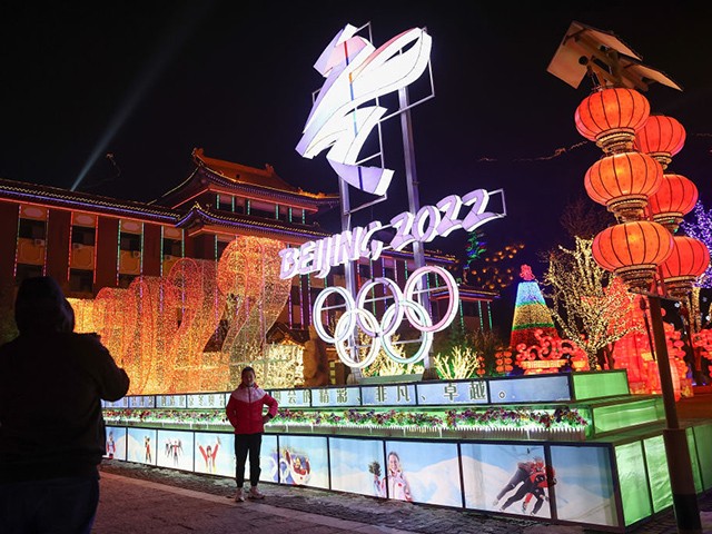 BEIJING, CHINA - FEBRUARY 26: People wear protective masks as they walk front the logos of the 2022 Beijing Winter Olympics at Yanqing Ice Festival on February 26, 2021 in Beijing, China. The Festival comes at the final day of the Chinese Lunar New Year celebrations. (Photo by Lintao Zhang/Getty Images)