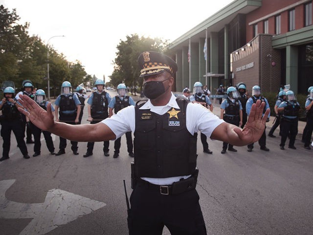 CHICAGO, ILLINOIS - AUGUST 11: A Chicago police officer attempts to deescalate tension as Englewood residents clash with demonstrators protesting outside the 7th District station of the Chicago Police Department on August 11, 2020 in Chicago, Illinois. The protest was held in response to the August 9 shooting and wounding …