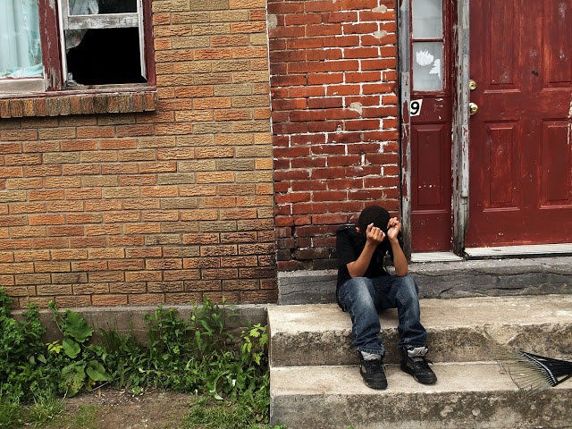 UTICA, NY - MAY 14: A child sits on a stoop in a working class section of Utica on May 14, 2012 in Utica, New York. Like many upstate New York communities, Utica is struggling to make the transition from a former manufacturing hub. The city's individual poverty rate is …