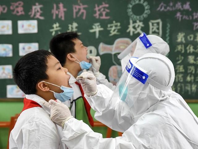 This photograph taken on August 17, 2020 shows a medical worker taking a swab sample from an elementary school student, to be tested for the COVID-19 coronavirus before schools open for the new semester, in Handan in China's northern Hebei province. (STR/AFP via Getty Images)