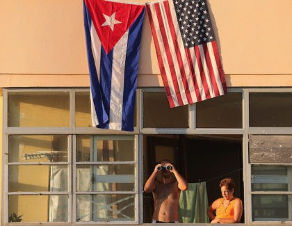 Cubans look out their window across the street from the newly reopened U.S. Embassy in hopes of watching the flag-raising ceremony August 14, 2015 in Havana, Cuba. The first American secretary of state to visit Cuba since 1945, Secretary of State John Kerry visited the reopened embassy, a symbolic act …