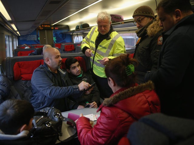 PADBORG, DENMARK - JANUARY 06: A Danish policeman checks the identity papers of passengers on a train arriving from Germany on January 6, 2016 in Padborg, Denmark. Denmark introduced a 10-day period of passport controls and spot checks on Monday on its border to Germany in an effort to stem …
