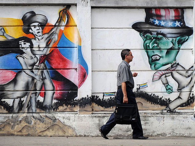 A person passes by a mural painting with a caricature of US President George W.Bush (R) in Caracas on September 12, 2008. The US Treasury announced Friday it was freezing any US assets of two senior Venezuelan officials and a former official after accusing them of aiding Colombian rebels involved …