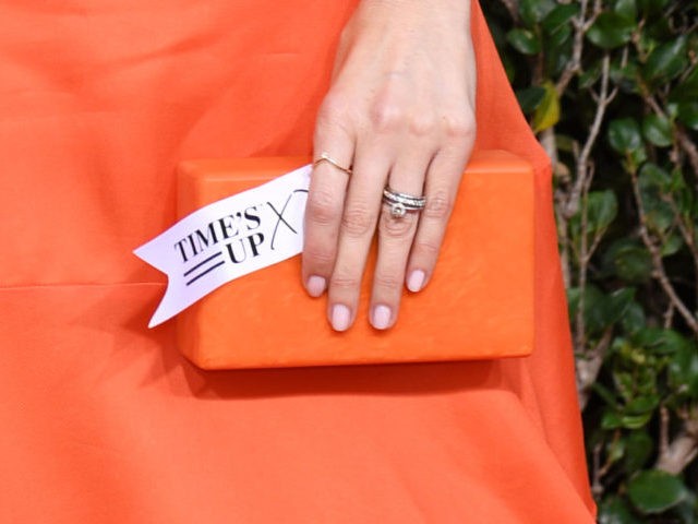 US actress D'Arcy Carden holds a tag reading "Time's Up" as she arrives for the 76th annua