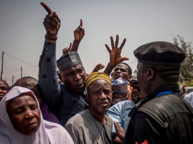 People talk to a policeman at Badarawa Junction polling station in Kaduna on February 23,