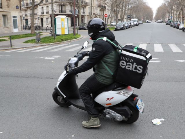 An Uber Eats delivery man rides a moped in Paris on March 22, 2020, as a strict lockdown is in effect to limit the spread of the COVID-19 caused by novel coronavirus in the country prohibiting all but essential outings. (Photo by Ludovic MARIN / AFP) (Photo by LUDOVIC MARIN/AFP …