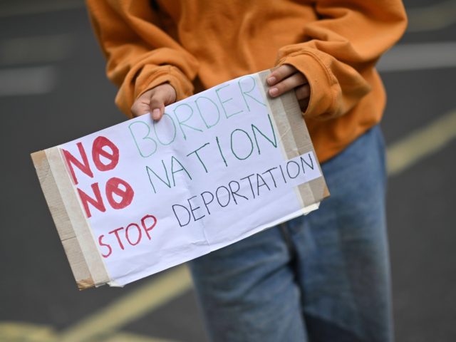 A protester carries a placard at a demonstration to highlight conditions inside Brook House immigration removal centre, outside the Home Office in London on August 23, 2020. - Migrants who crossed the Channel to the UK are on hunger strike in a detention centre as they face deportation next week, …