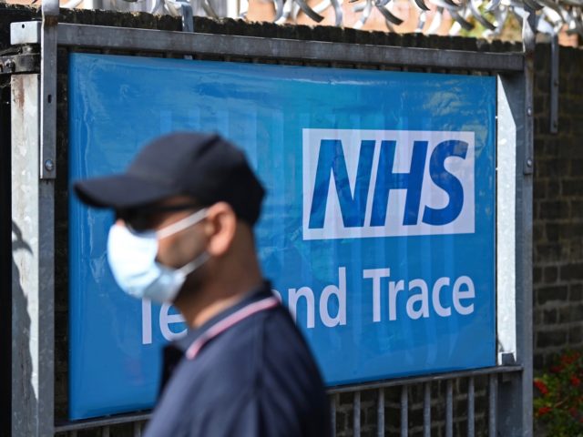 A worker wearing a face mask or covering due to the COVID-19 pandemic, stands near a sign for Britain's NHS (National Health Service) Test and Trace service, as he works at the entrance to a novel coronavirus walk-in testing centre in East Ham in east London, on September 17, 2020. …