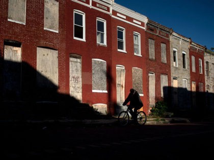 A man rides a bike past boarded up row houses in the Broadway East neighborhood on October