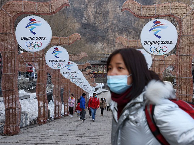 BEIJING, CHINA - FEBRUARY 26: People wear protective masks as they walk front the logos of