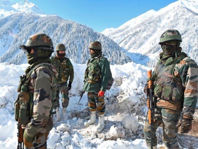Indian army soldiers stand on a snow-covered road near Zojila mountain pass that connects Srinagar to the union territory of Ladakh, bordering China on February 28, 2021. (Photo by TAUSEEF MUSTAFA / AFP) (Photo by TAUSEEF MUSTAFA/AFP via Getty Images)