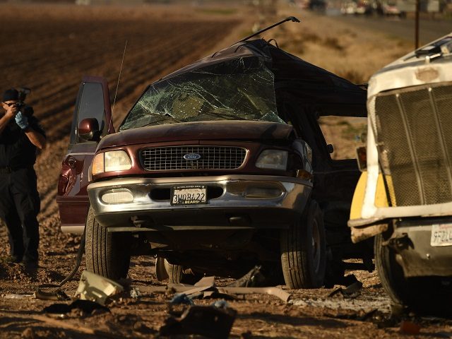 Investigators look over the scene of a crash between an SUV and a semi-truck full of gravel near Holtville, California on March 2, 2021. - At least 13 people were killed in southern California on Tuesday when a vehicle packed with passengers including minors collided with a large truck close …