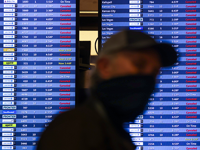 A man walks past a display board showing mostly canceled flights at Denver International A