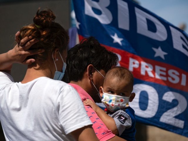 Migrants are seen with a US President Joe Biden campaign flag in the background at a camp