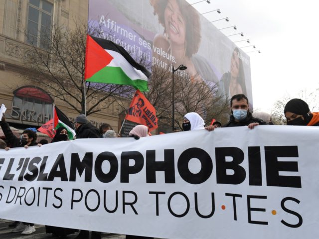 Protesters hold a banner and a Palestinian flag during a demonstration against a bill dubb