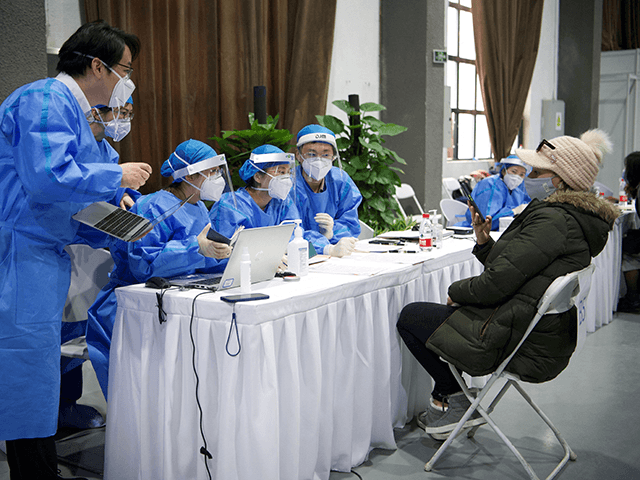 Medical workers collect information from a foreign journalist (R) waiting to be inoculated