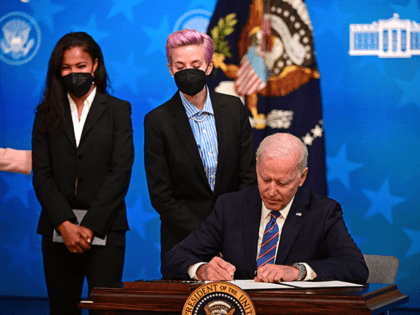 US President Joe Biden (R) signs a proclamation marking National Equal Pay Day 2021, flanked by US soccer players Margaret Purce (L) and Megan Rapinoe, during an Equal Pay Day event in the South Court Auditorium of the White House in Washington DC, on March 24, 2021. (Photo by JIM …