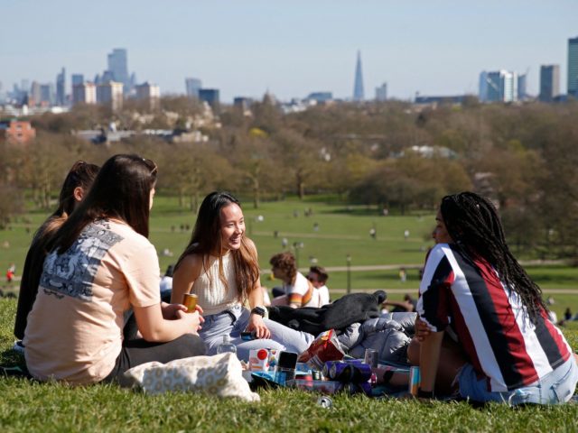 A group sit and chat in the warm weather on Primrose Hill in London on March 29, 2021, as England's third Covid-19 lockdown restrictions ease, allowing groups of up to six people to meet outside. - England began to further ease its coronavirus lockdown on Monday, spurred by rapid vaccinations, …