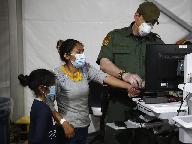 A migrant and her daughter have their biometric data entered at the intake area of the Donna Department of Homeland Security holding facility, the main detention center for unaccompanied children in the Rio Grande Valley in Donna, Texas on March 30, 2021. (Photo by Dario Lopez-Mills / POOL / AFP) …