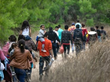 MISSION, TEXAS - MARCH 23: Asylum seekers, most from Honduras, walk towards a U.S. Border Patrol checkpoint after crossing the Rio Grande from Mexico on March 23, 2021 near Mission, Texas. A surge of migrant families and unaccompanied minors is overwhelming border detention facilities in south Texas' Rio Grande Valley. …