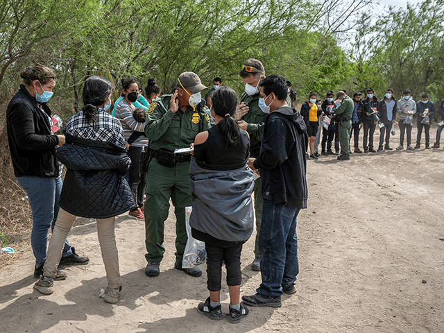 U.S. Border Patrol agents question families as a group of unaccompanied minors (R), awaits