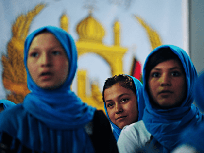 Afghan schoolgirls stand onstage in front of their country's coat-of-arms as they prepare to sing the national anthem during a campaign event for Habiba Surabi, the second vice-president candidate running on the ticket of presidential candidate Zalmai Rassoul, at a local hall in Kabul on March 31, 2014. Officially there …