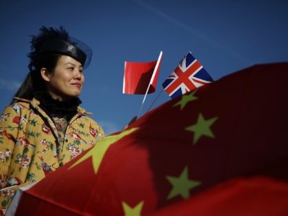 BARKING, ENGLAND - JANUARY 18: A woman holds a Union flag and a Chinese Flag as a train engine pulls carriages that started their Journey in Yiwu in China into Barking rail freight terminal on January 18, 2017 in Barking, England. After travelling for 16 days and covering around 7,456 …