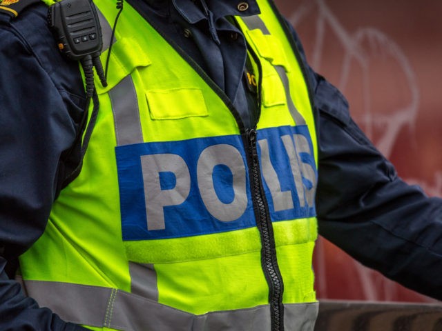 Close up of Swedish police officer wearing a luminous yellow green vest with police text.