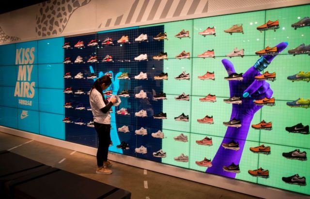 An employee works next to shoes on display inside the flagship store of sporting-goods gia