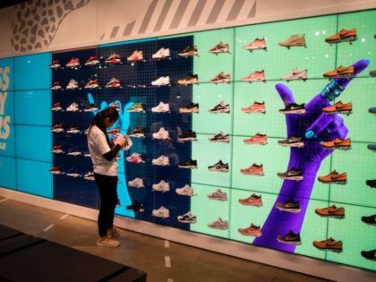 An employee works next to shoes on display inside the flagship store of sporting-goods giant Nike in Shanghai on March 16, 2017. US sporting-goods giant Nike has become the latest foreign brand to receive a high-profile rebuke from an influential Chinese consumer-affairs programme that has previously forced Apple and McDonald's …