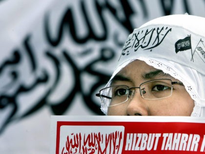 JAKARTA, INDONESIA: An activist of the Islamic group, Hizbut Tahrir Indonesia, displays an anti-Israeli placard standing in front of an Islamic flag during a demonstration in Jakarta, 06 July 2006. Several hundreds of men, women and children took part in the protest to vitrine their support to the Palestinian people …