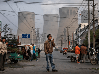 Chinese street vendors and customers gather at a local market outside a state owned Coal fired power plant near the site of a large floating solar farm project under construction by the Sungrow Power Supply Company on a lake caused by a collapsed and flooded coal mine on June 14, …