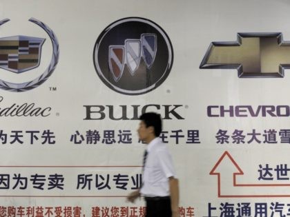 A salesman walks past a billboard featuring the trademarks belonging to US auto maker General Motors at a dealership in Beijing on June 2, 2009. The China unit of auto maker General Motors continues to expand despite the woes of its parent, which this week filed for bankruptcy, with new …