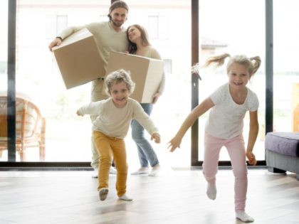 Funny happy kids running into new house on moving day, excited children boy and girl play inside luxury big modern room while smiling parents entering own home, family mortgage and relocation concept