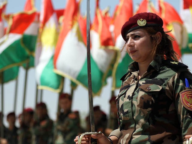 A woman fighter of the Iraqi Kurdish Peshmerga attends a ceremonial line-up past flying flags of Iraq's autonomous Kurdistan region, during a training session by German military officers during the German Defence Minister's visit at a facility on the outskirts of Arbil, the capital of the autonomous region, on August …