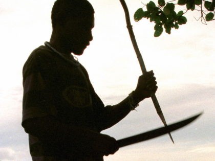In this file photo, a Guadalcanal guard sharpens a stake with his machette near the abandoned village of Vilu, Solomon Islands 20 June 1999 after the area was cleared of Malaitans by the Guadalcanal Liberation Army. (Torsten Blackwood/AFP via Getty Images)