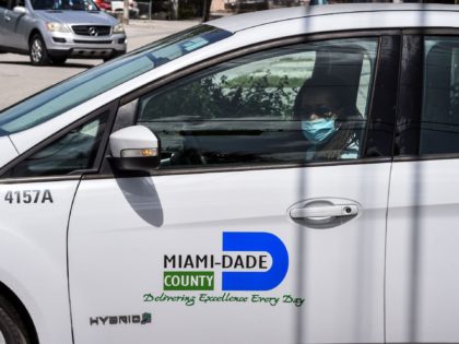 A Miami-Dade County official wears a face mask as she drives through a neighbourhood of Miami, Florida to distribute bags with masks, sanitizers, gloves and to educate people on how to stay safe from COVID-19, on June 30, 2020. - House to house, a group of Florida's workers hand out …