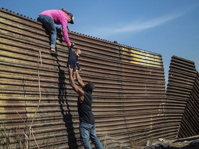 In this file photo, a group of Central American migrants climb the border fence between Mexico and the United States, near El Chaparral border crossing, in Tijuana, Baja California State, Mexico, on November 25, 2018. (Pedro Pardo/AFP via Getty Images)