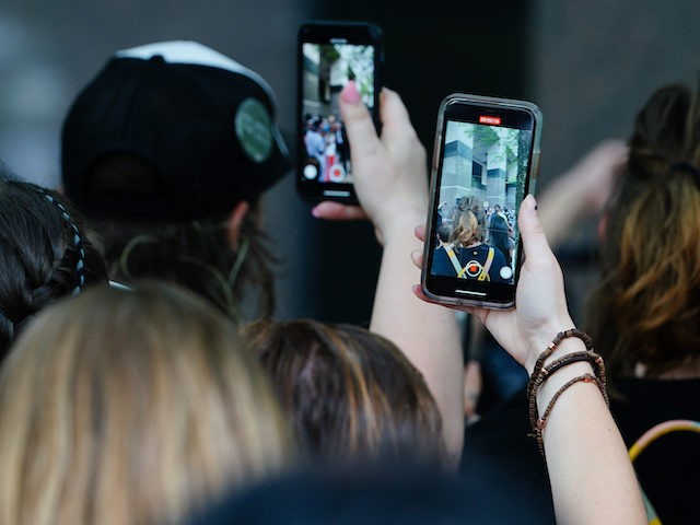 People use their cell phones to record a speaker during a protest over the death of George