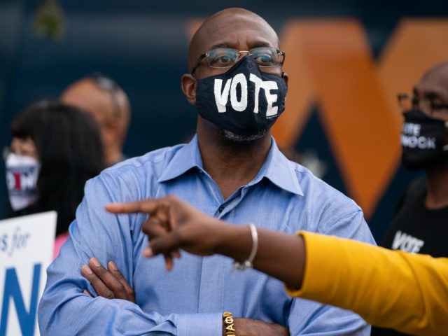 Democratic Senate candidate Reverend Raphael Warnock attends a rally on October 24, 2020, in Duluth, Georgia. - Neighbors and volunteers are handing out water and snacks to the masked voters waiting patiently in line to cast their ballots on a hot October day in the Atlanta suburb of Smyrna. Americans …
