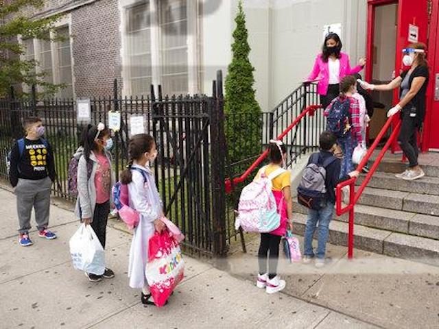 Students line up to have their temperature checked before entering PS 179 elementary schoo