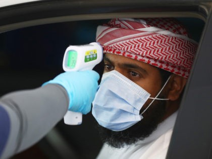 A medical worker, wearing disposable gloves , measures the temperature of a man at a coronavirus drive-through screening center on April 01, 2020 in Abu Dhabi, United Arab Emirates. (Francois Nel/Getty Images)