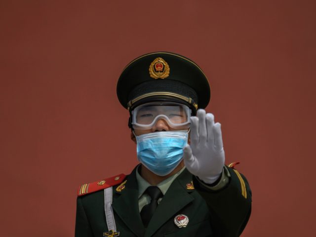 BEIJING, CHINA - MAY 01: A Chinese paramilitary police officer gestures as he wears a protective mask while standing guard at the entrance to the Forbidden City as it re-opened to limited visitors for the May holiday, on May 1, 2020 in Beijing, China. Beijing lowered its risk level after …