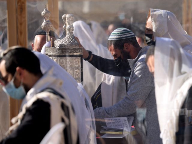 Jewish worshippers hold a Torah scroll as they recite the Priestly Blessing on the holiday