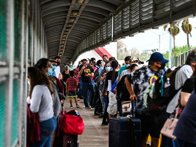 Migrants mostly form Central America wait in line to cross the border at the Gateway International Bridge into the US from Matamoros, Mexico to Brownsville, Texas, on March 15, 2021. - It's the new normal for migrant families under President Joe Biden, after the harsh "zero tolerance" approach of Donald …