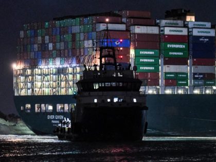 This picture taken late on March 27, 2021 shows a view of a tugboat by the Panama-flagged MV 'Ever Given' (operated by Taiwan-based Evergreen Marine) container ship, which has been wedged diagonally across the span of the canal about six kilometres north of the Suez Canal's entrance by the Red …