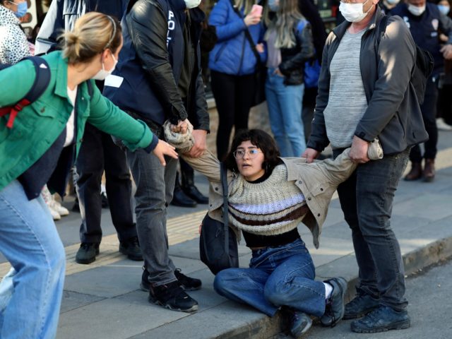 A woman reacts as riot police officers detain a student during a protest, in Ankara, Turke
