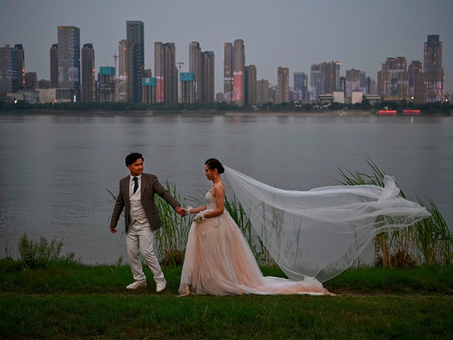 A couple poses during a wedding photo shoot by wedding photographer Zhang (not pictured), next to Yangtze River in Wuhan, in China's central Hubei province on May 16, 2020. - Authorities in the pandemic ground zero of Wuhan have ordered mass COVID-19 testing for all 11 million residents after a new cluster of cases emerged over the weekend. (Photo by Hector RETAMAL / AFP) (Photo by HECTOR RETAMAL/AFP via Getty Images)
